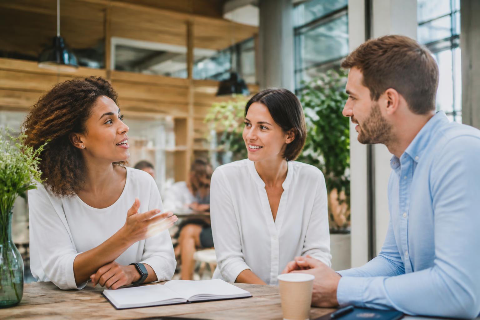 Kleine Gruppe in einem hellen, sommerlichen Workshopraum — eine Person hört aufmerksam zu